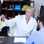physiotherapist explaining spine model to patient U3SPSCX 02